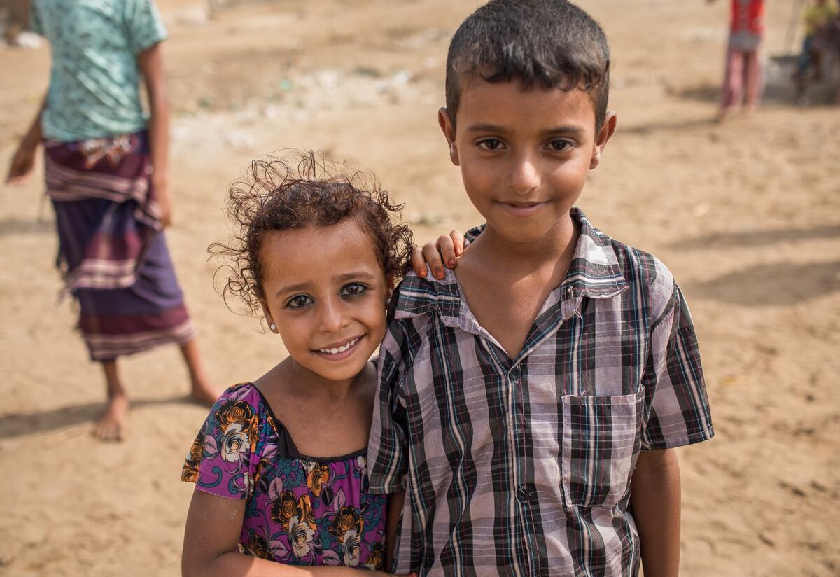 A girl and boy stand in front of their home in Al Buraiqeh, a remote village on the outskirts of Aden, Yemen, where IRC health teams provide care for malnutrition,