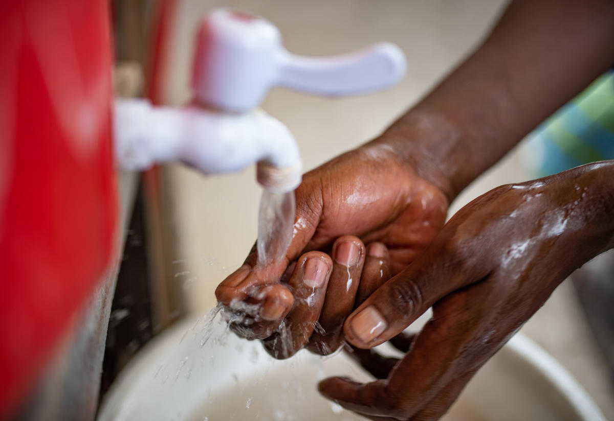 A health worker in the Democratic Republic of Congo washes his hands at a water tap