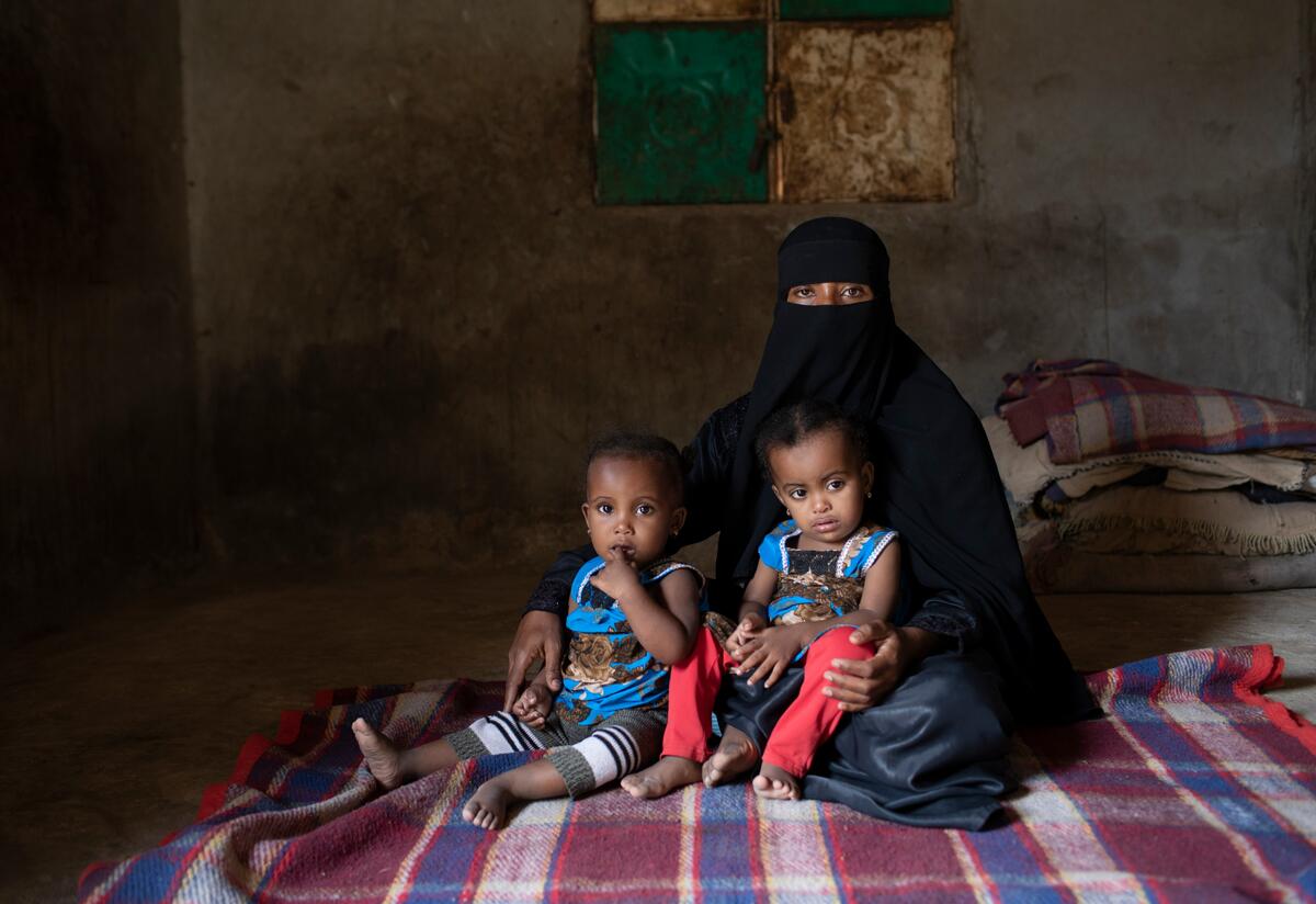 Fulla sits with her young twin daughters, who received medical help from the International Rescue Committee when they were diagnosed as acutely malnourished.