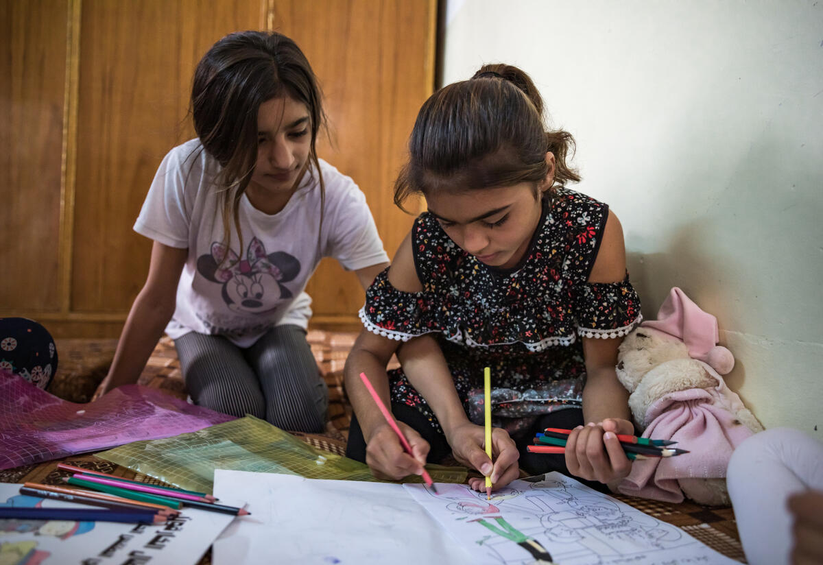 Darin and her siblings color in one of Darin’s activities books. Darin, a young Yazidi girl living in Sinjar, Iraq participates in summer activities at a public school supported by the International Rescue Committee Two young sisters in Sinjar, Iraq sit on the floor coloring in an activity book