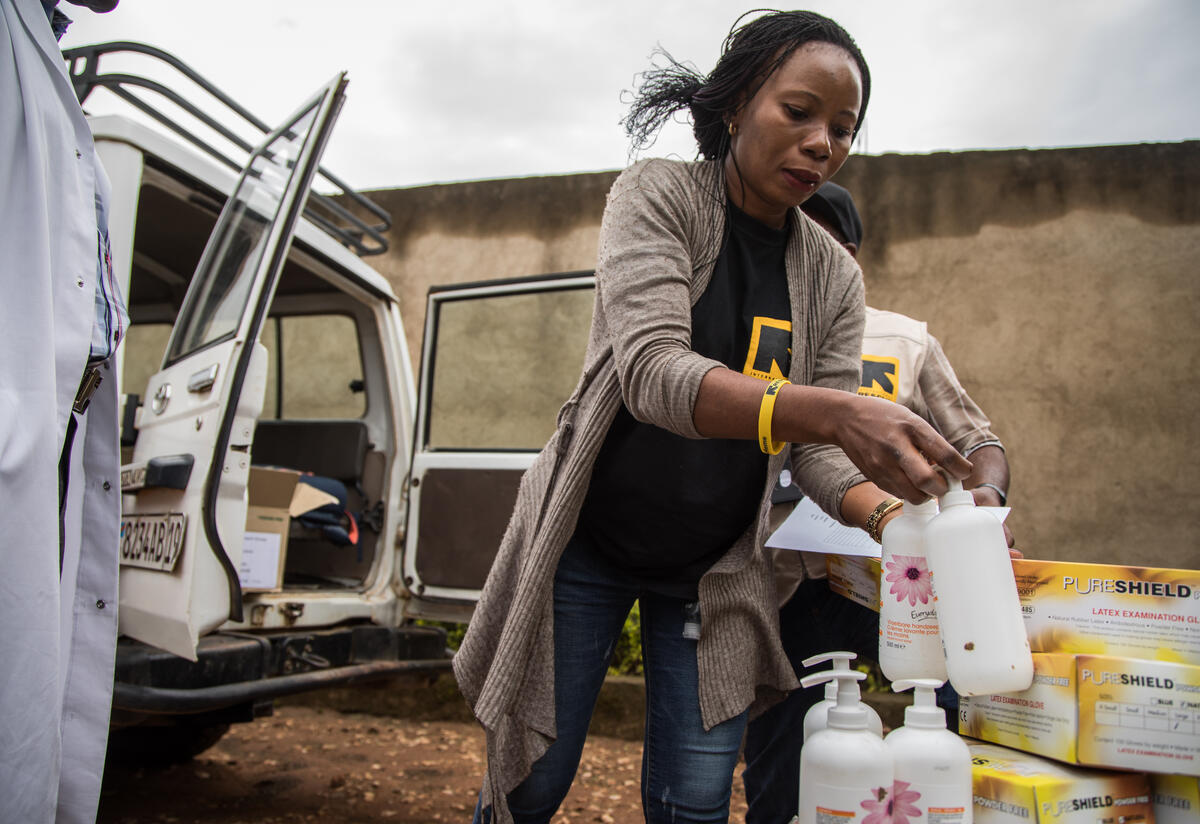 Dr. Sylvie Musema Ngimba of the IRC unloads personal protective eqipment and sanitizer from a 4-wheel-drive vehicle.