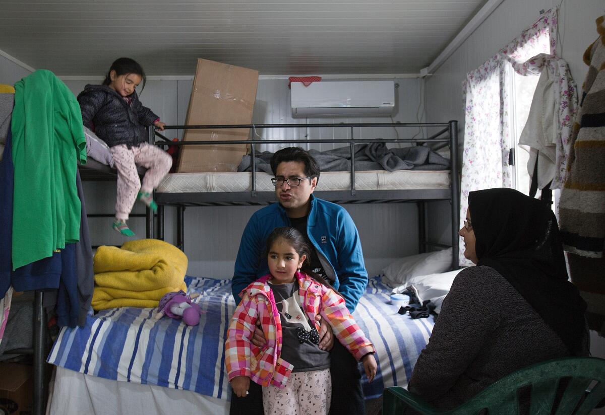 Parents and their two young children in their corrugated iron shelter in Moria refugee camp, Greece