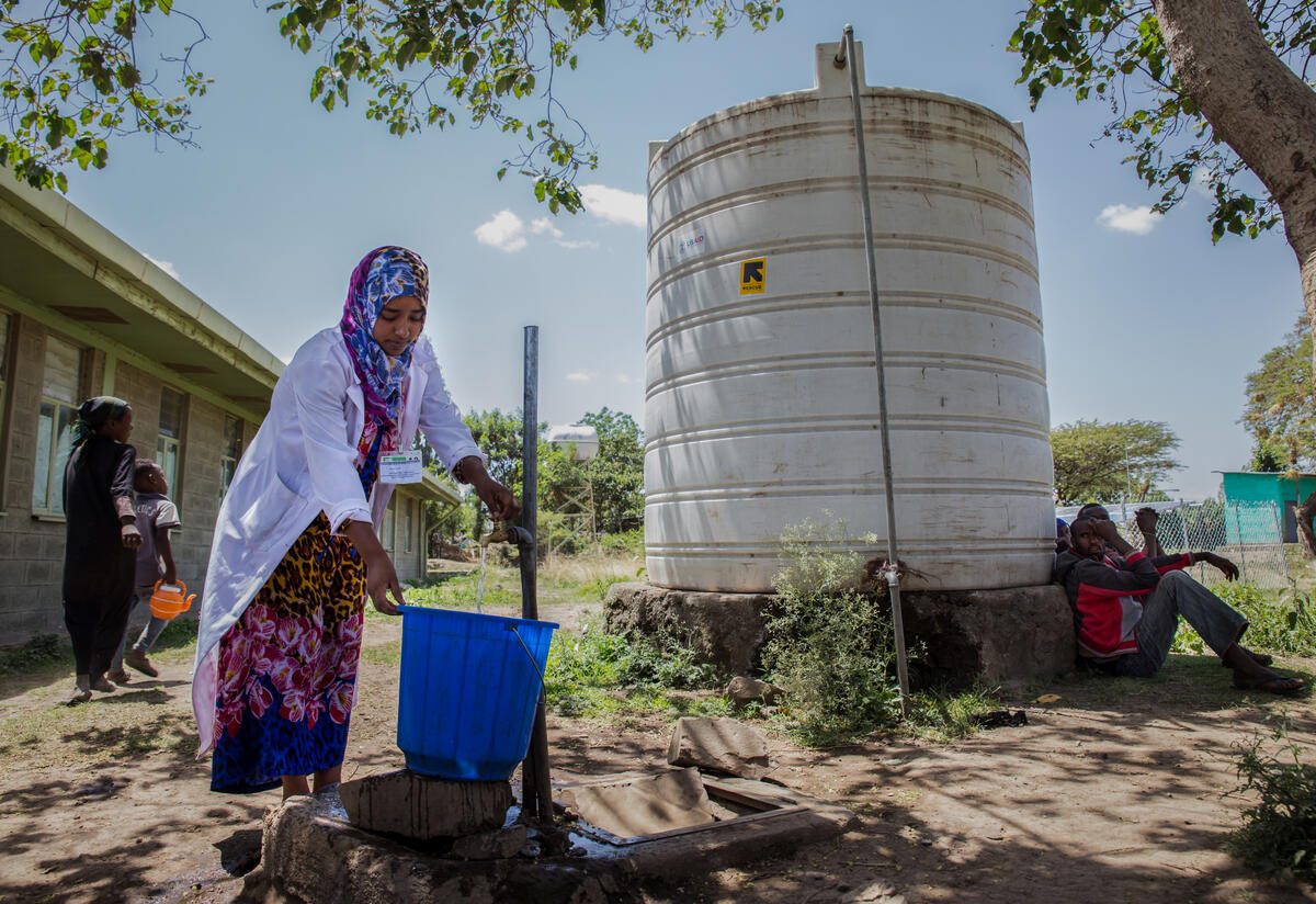 An IRC staff member collects water at a tap in Ethiopia. The IRC is responsing to the Tigray crisis.
