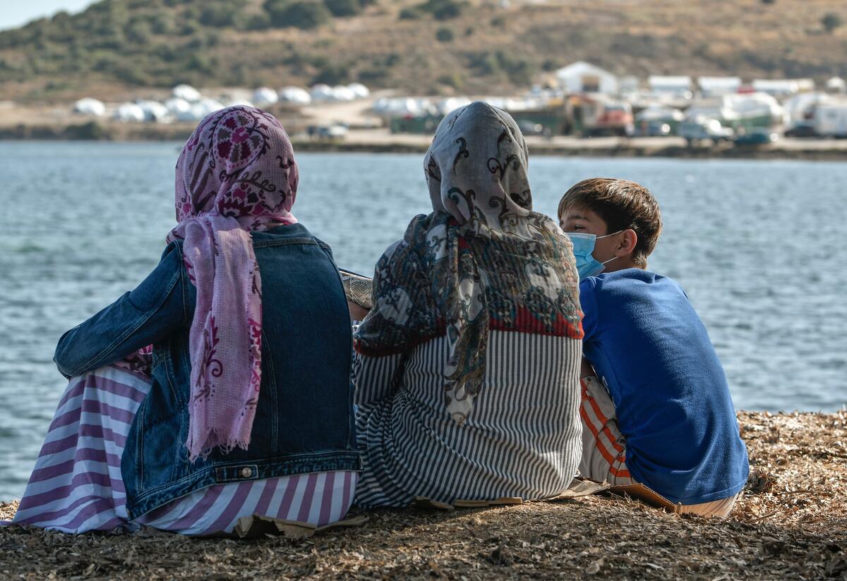 Rahima and two of her children sit together facing the sea in their refugee camp on the Greek island of Lesbos.