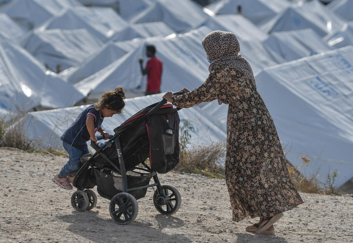 A 33-year-old Syrian refugee, wearing a face mask to protect herself from the coronavirus, pushes two of her children in a stroller past rows of tents in a crowded refugee camp on the Greek island of Lesbos.