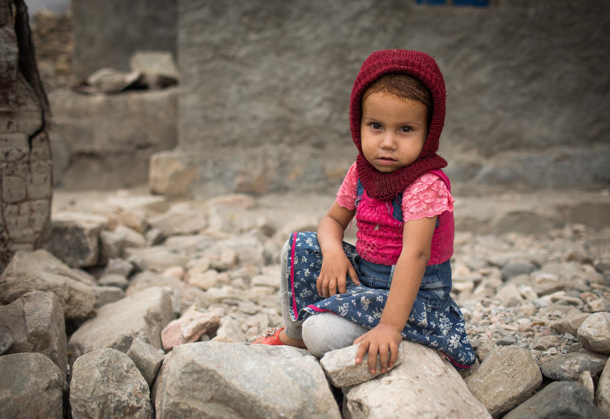 A young girl sits on the ground in a village in Yemen