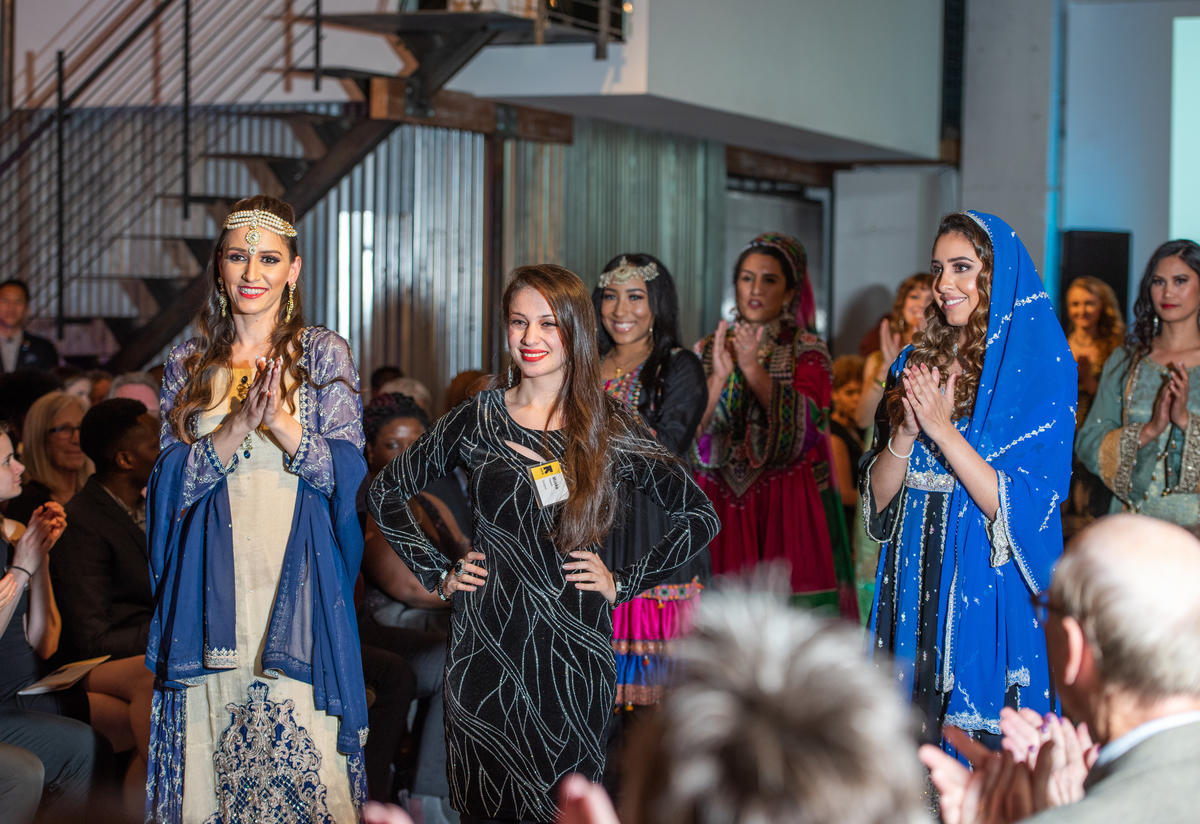 Muska Haseeb, a refugee from Afghanistan, fashion designer, and new US citizen, poses with models wearing her designs at HOPE Couture.