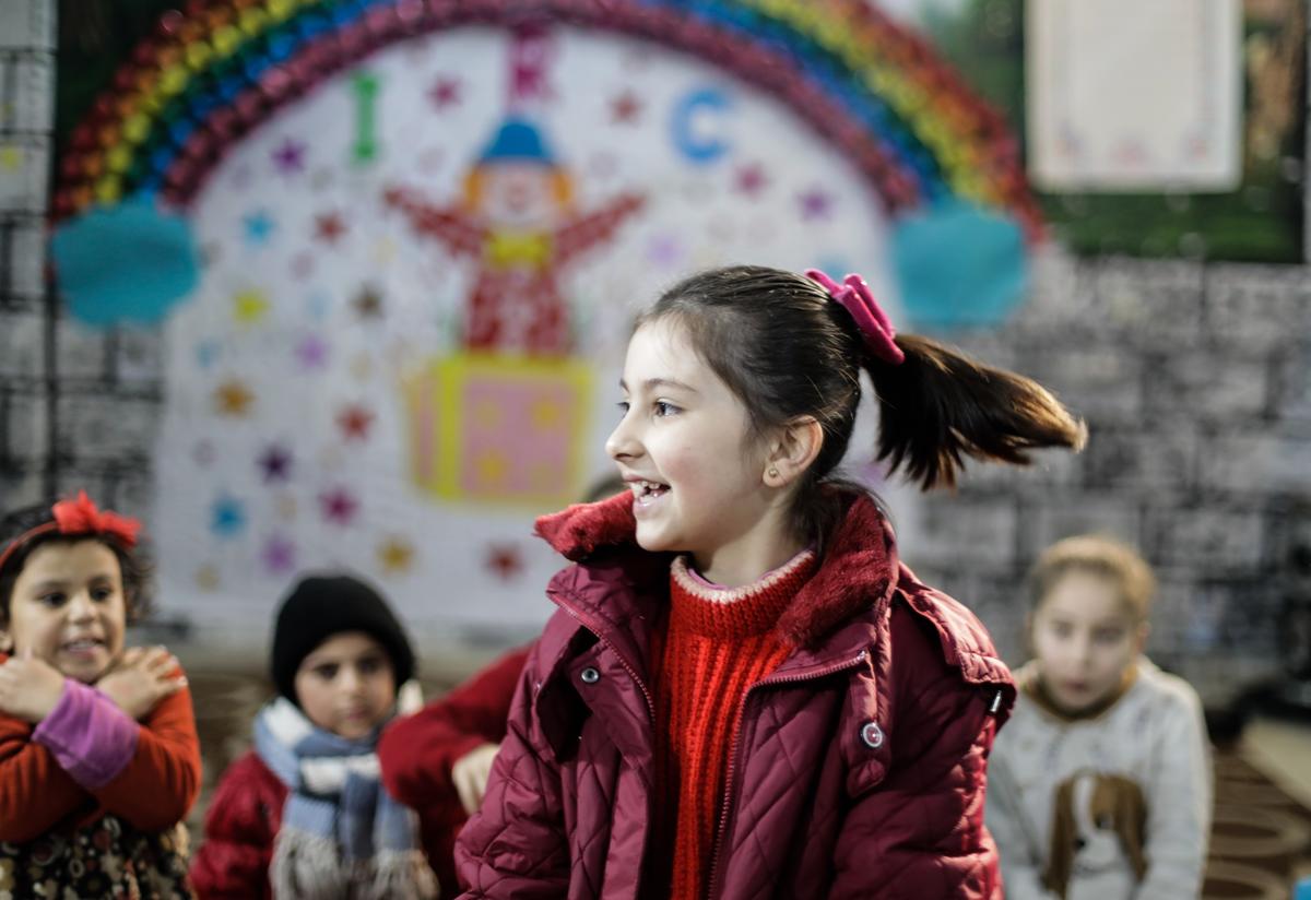Ponytail flying, 9-year-old Abeer plays in an IRC children's safe space in Idlib, Syria