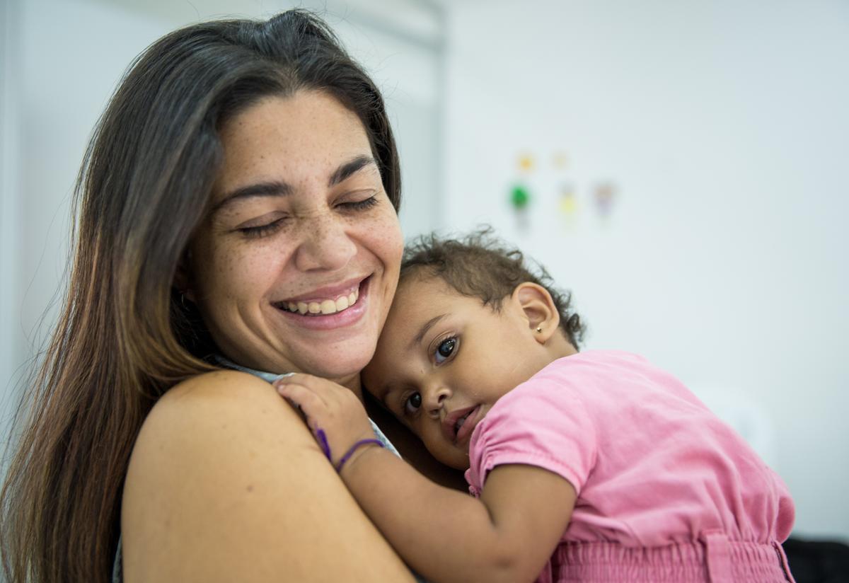 A smiling Andrea holds her sleepy younger daughter at the IRC care center in Cúcuta.