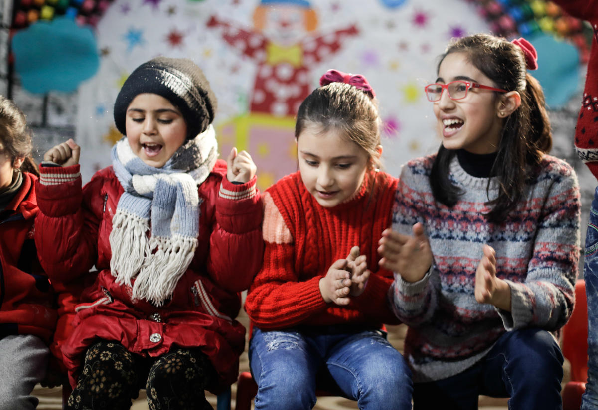 Abeer and her sister Mariam sit and sing with other girls at an IRC children's safe space in Syria.