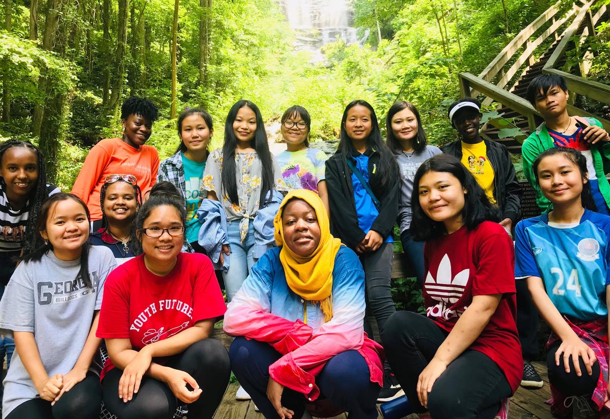 We rounded off the summer with an overnight camping trip, made possible through generous sponsorship from the Sierra Club Inspiring Connections Outdoors program. Students and staff take a group picture outside, surrounded by trees.