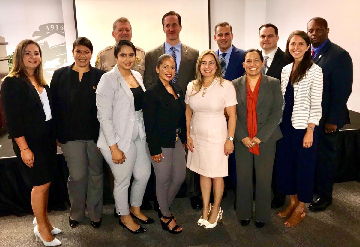 Members of the Federal South Florida Human Trafficking Task Force hosted an event to raise awareness of the National Human Trafficking Hotline. A group of men and women wearing professional business attire smile and pose for a group picture.