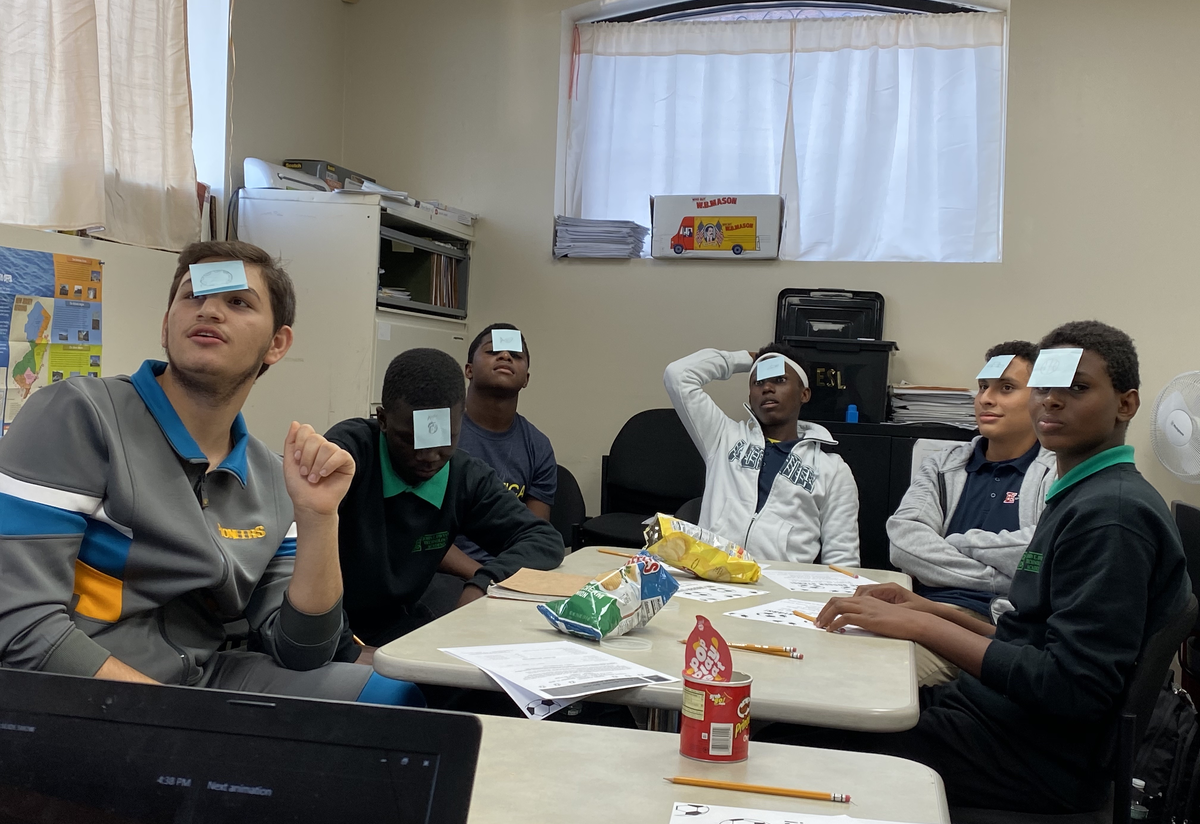 students playing a social-emotional game students gathered at a table playing a post-it game