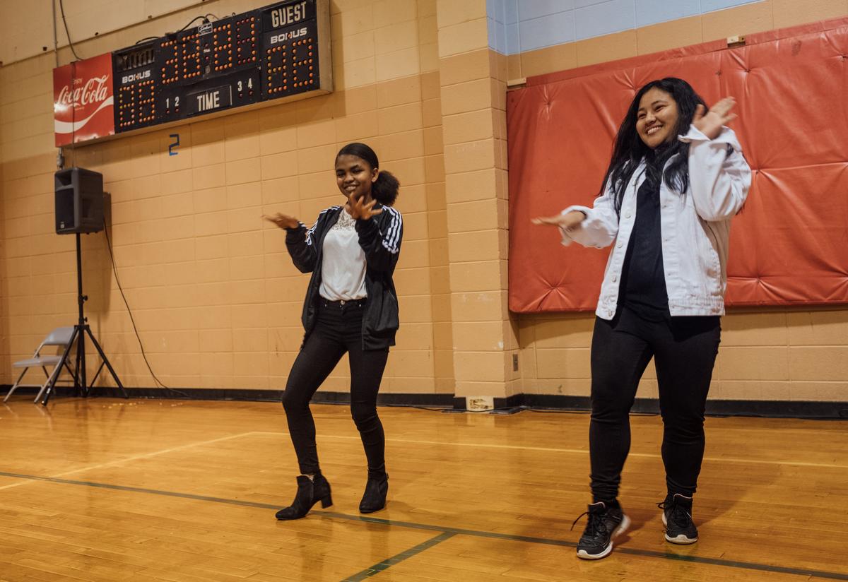 The IRC in Atlanta's 18th annual Thanksgiving Feast. Two young women from the IRC in Atlanta's youth programs dance energetically together, side by side, as part of the entertainment portion of the Thanksgiving Feast.