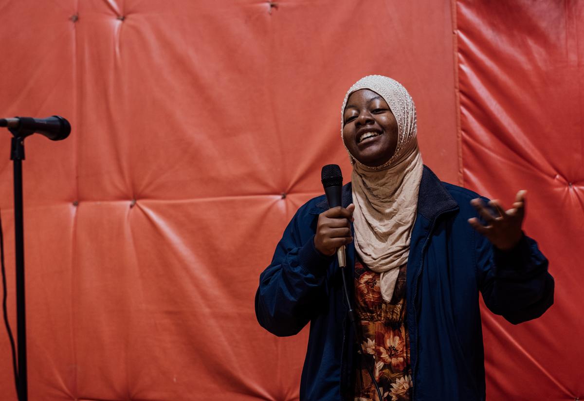 The IRC in Atlanta's 18th annual Thanksgiving Feast. A young woman from the IRC in Atlanta's youth program holds a microphone in one hand as she sings passionately to attendees as part of the entertainment portion of the feast.