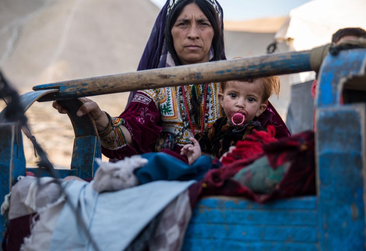A mother rocks her sick child in a camp in Badghis in Afghanistan, where the International Rescue Committee supports displaced families. A mother rocks her sick child, who is sucking on a pacifier, in a camp in Afghanistan's Badghis province, where the IRC supports displaced families.