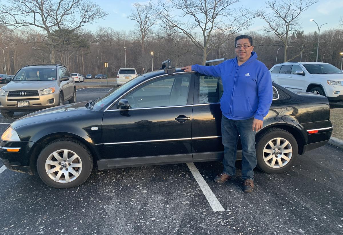 IRC client standing with his new car Liber client standing outside with his new car