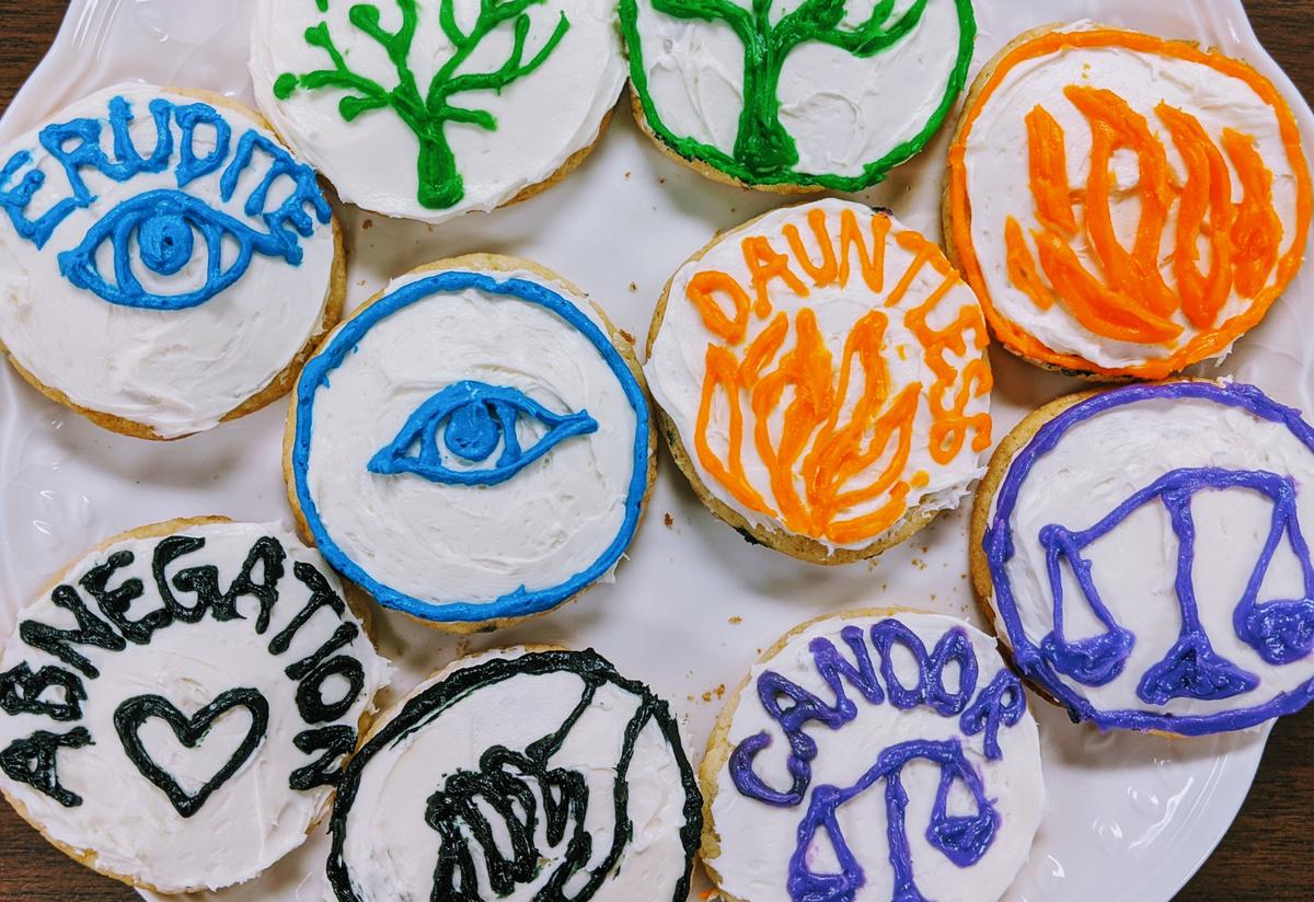 A plate of colorful, iced cookies with symbols including a tree, an eye, fire and scales, representing the factions from the book.