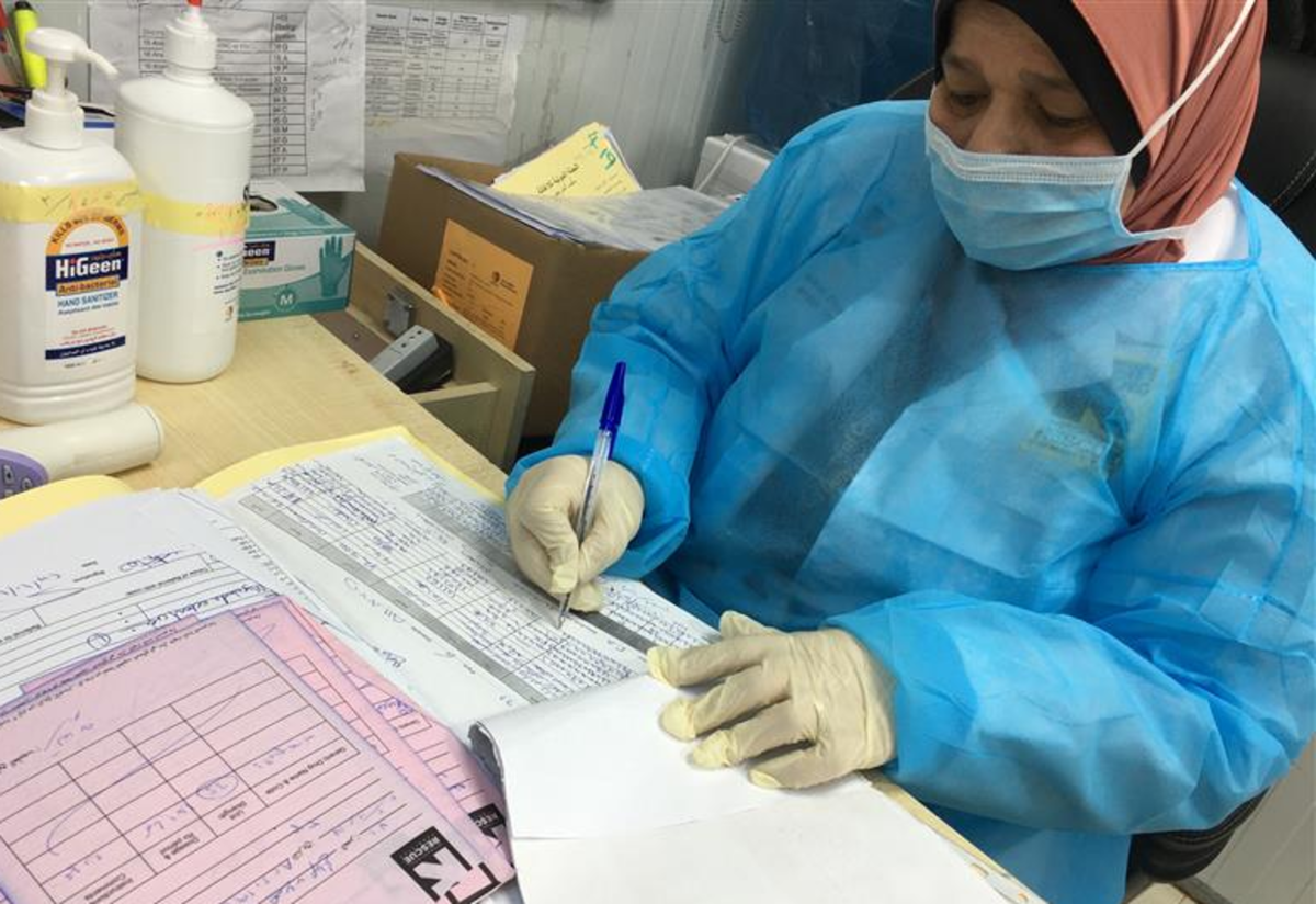 IRC’s frontline workers in Jordan continue to provide essential health services in refugee camps in Jordan. An IRC staff member in Jordan looks over paperwork.