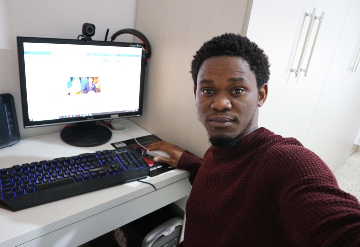 Henry, a Refugee.Info moderator, poses in front of his computer while sharing vital information with refugees and asylum seekers in Italy. 