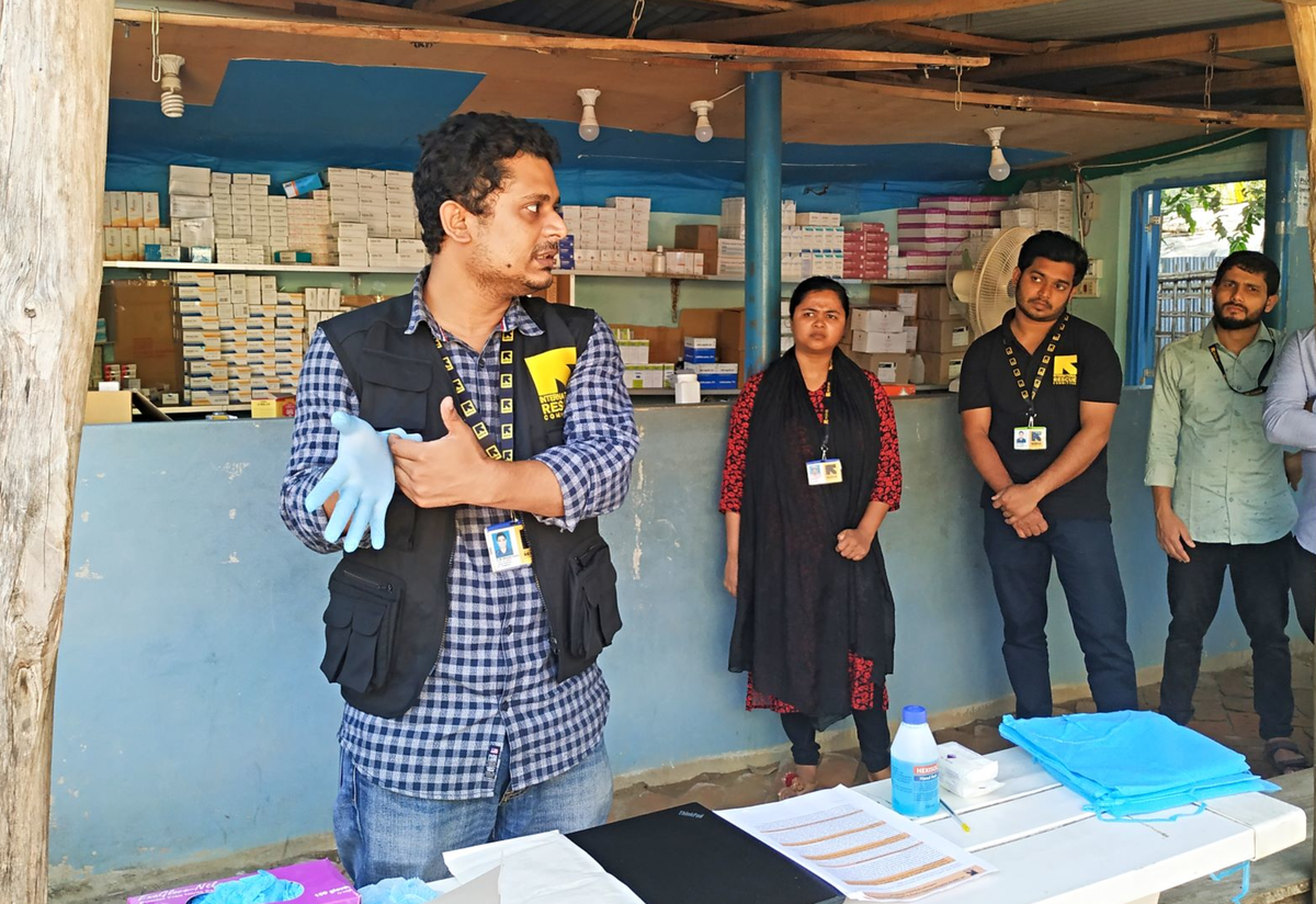 An IRC doctor demonstrates the proper way to put on gloves for health care workers and volunteers in an IRC health facility in Bangladesh. An IRC doctor demonstrates the proper way to put on gloves for health care workers and volunteers in an IRC health facility in Bangladesh.