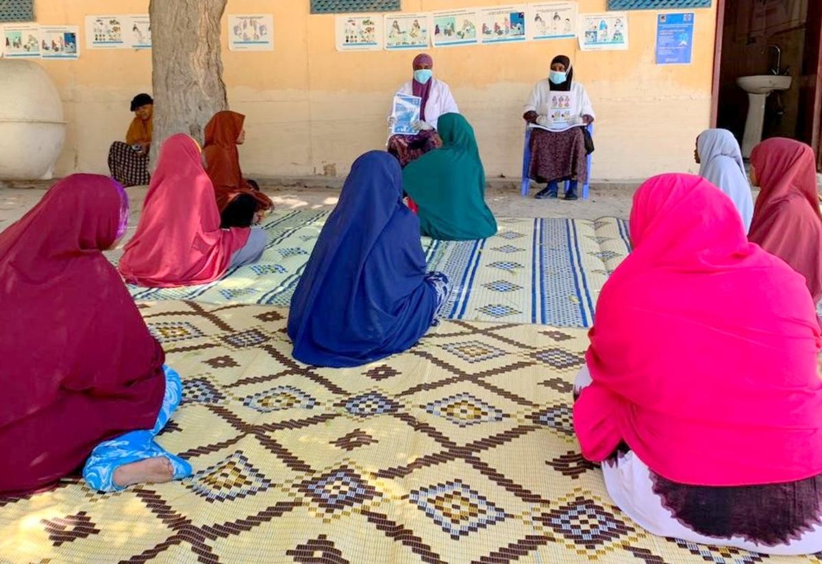 Health workers trained by the IRC conduct an education session for members of the community at Arif Health Clinic in Mogadishu, Somalia. Two health workers in masks speak to a group of women about the coronavirus in a health clinic in Mogadishu, Somalia.