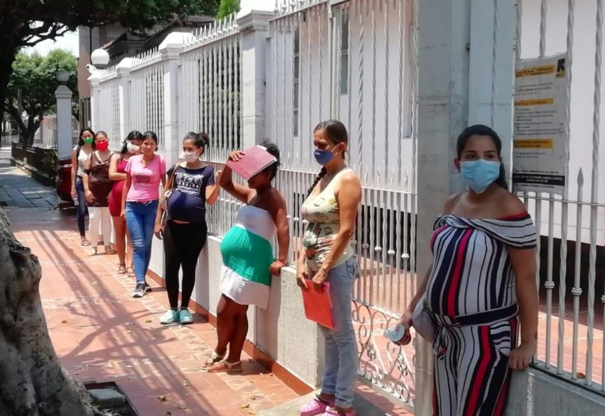 Patients wait outside—six feet apart—for their appointments in the IRC's maternal health clinic in Cúcuta, Colombia. Pregnant woman stand outside six feet apart from one another outside the IRC's maternal health clinic in Cúcuta, Colombia.
