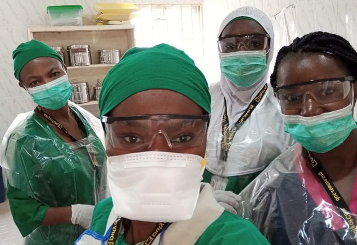 Midwives wearing personal protective equipment (PPE) at the reproductive health clinic in Bakassi Internally Displaced Person (IDP) camp in Maiduguri, Nigeria. Four midwives wearing scrubs and personal protective equipment (PPE), including masks, take a selfie at the reproductive health clinic in Bakassi Internally Displaced Person (IDP) camp in Maiduguri, Nigeria.