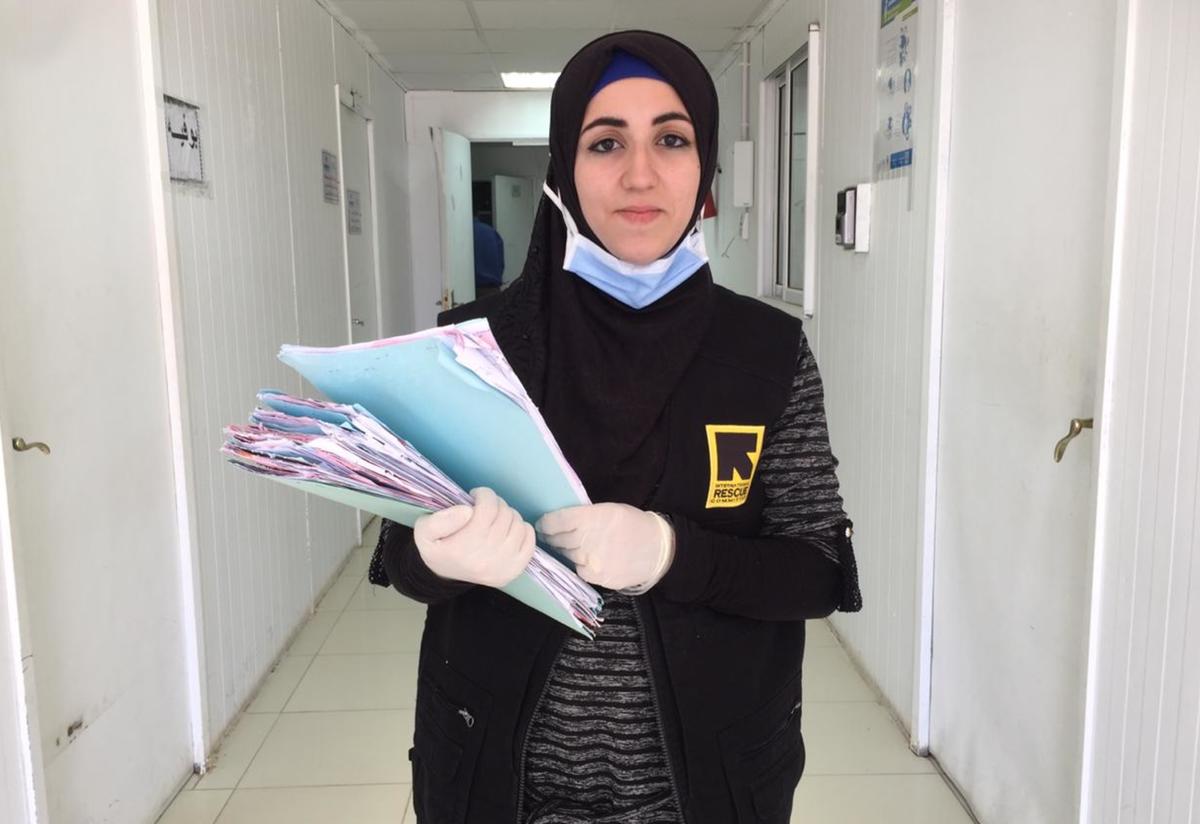 Doha Ibrahim Ammouri Doha Ibrahim Ammouri, holding files, walks in a hallway in an IRC reproductive health clinic. She is wearing a mask and gloves.