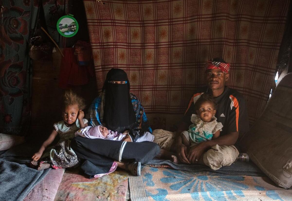 Bodor, 28, holding her baby daughter Enqath, sits with her husband and two children inside their tent. Bodor, 28, holding her baby daughter Enqath, sits with her husband and two children inside their tent. The baby is sitting on Bodor's lap and another child sits on her husband's lap. The whole family is looking at the camera.