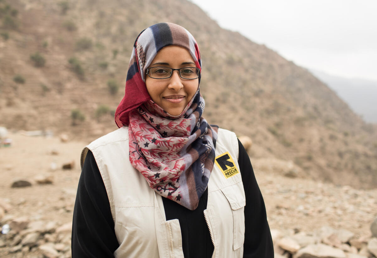 Dr Rasha Rashed Dr Rasha Rashed, wearing an IRC vest, stands outside in front of a desert landscape