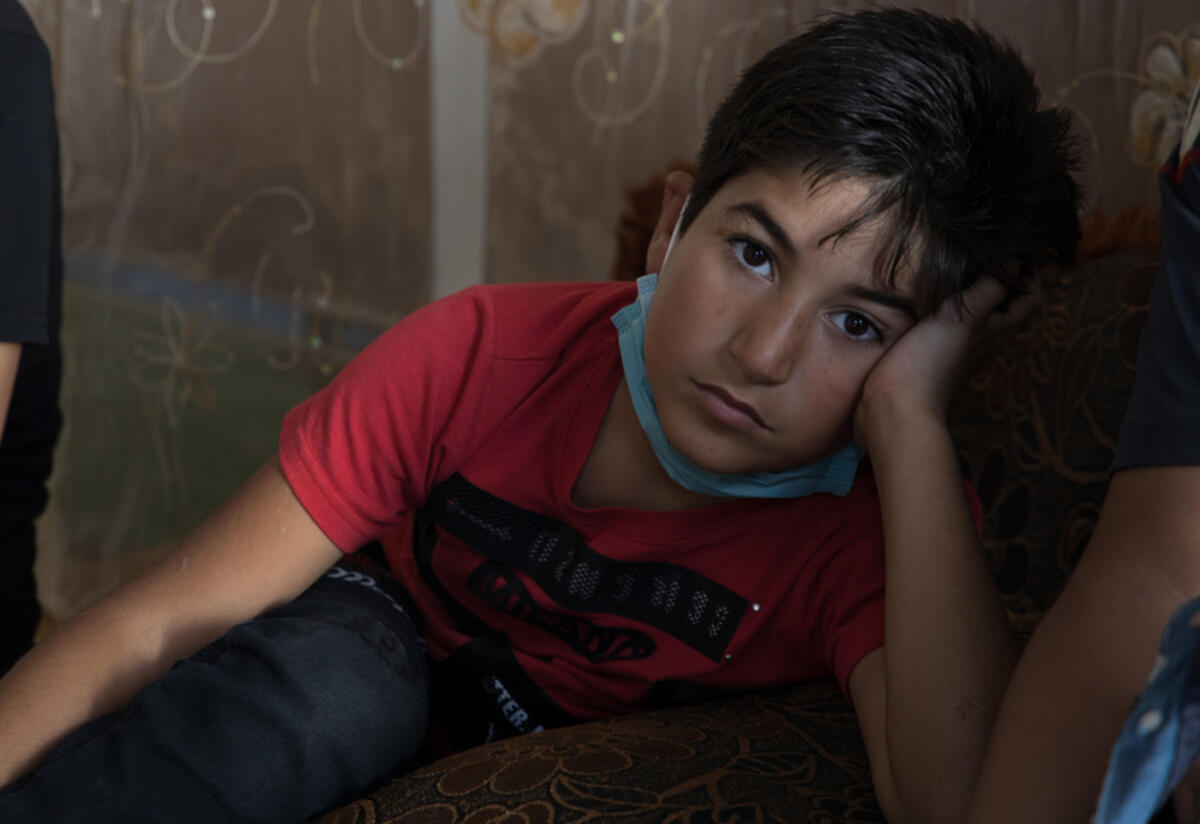 Nine-year-old Ahmad Nine-year-old Ahmad sits and looks at the camera with his head in his hand.