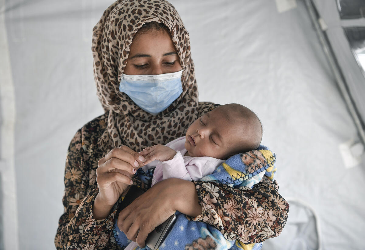 Ikram Ismail holds her infant daughter, touching her tiny fingertips
