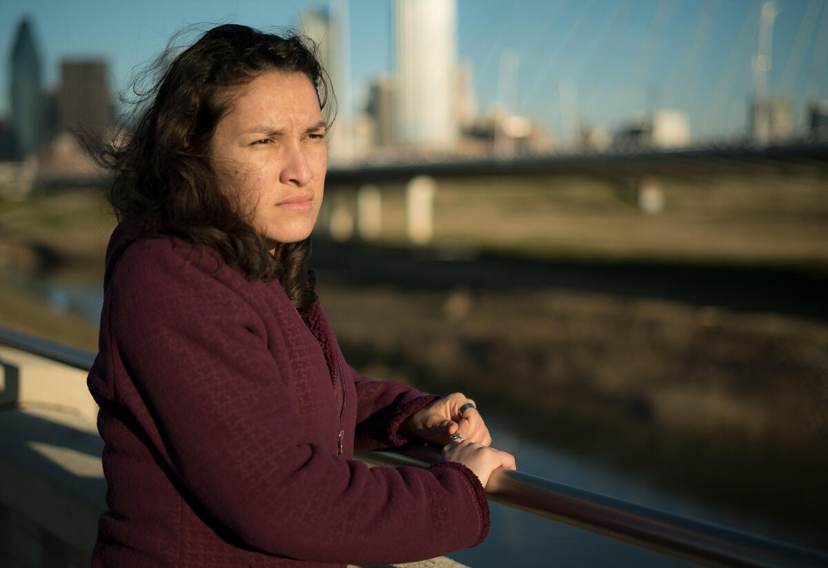 Valentina, a refugee from El Salvador, stands on a bridge in Dallas, TX, and looks out over the water. 
