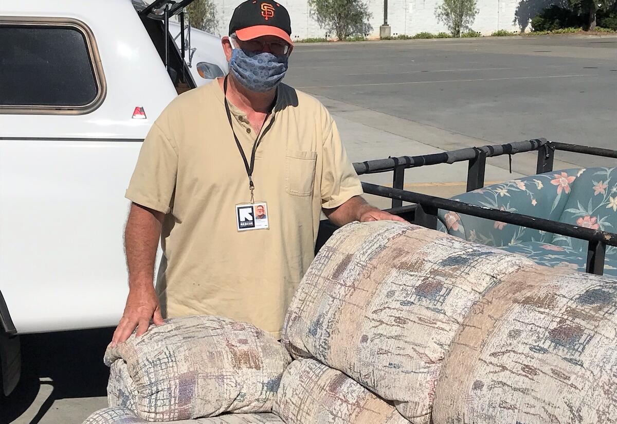 Ron Hand, Turlock Donation Delivery Volunteer Ron Hand is pictured outside in a parking lot with his truck and trailer loaded with a couch donation