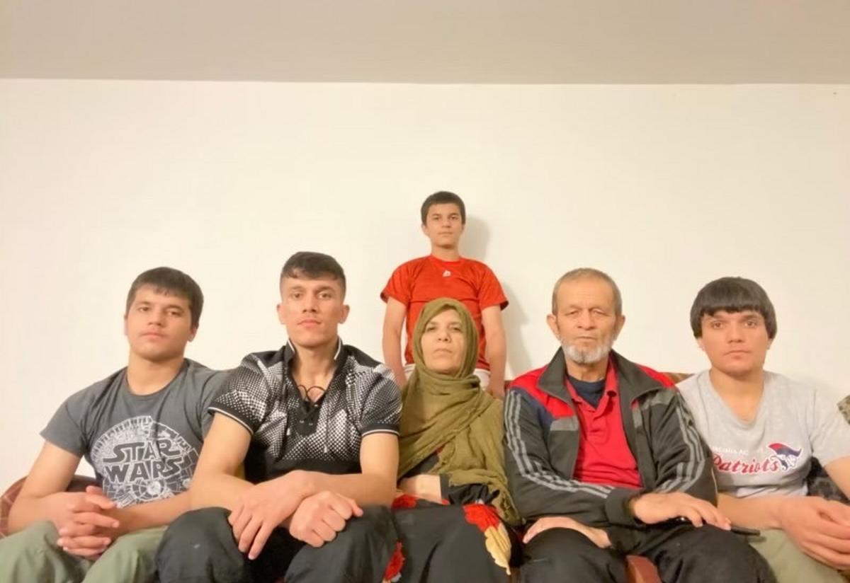 Mohammad and Nazifah sit on the couch, surrounded by thier four boys.