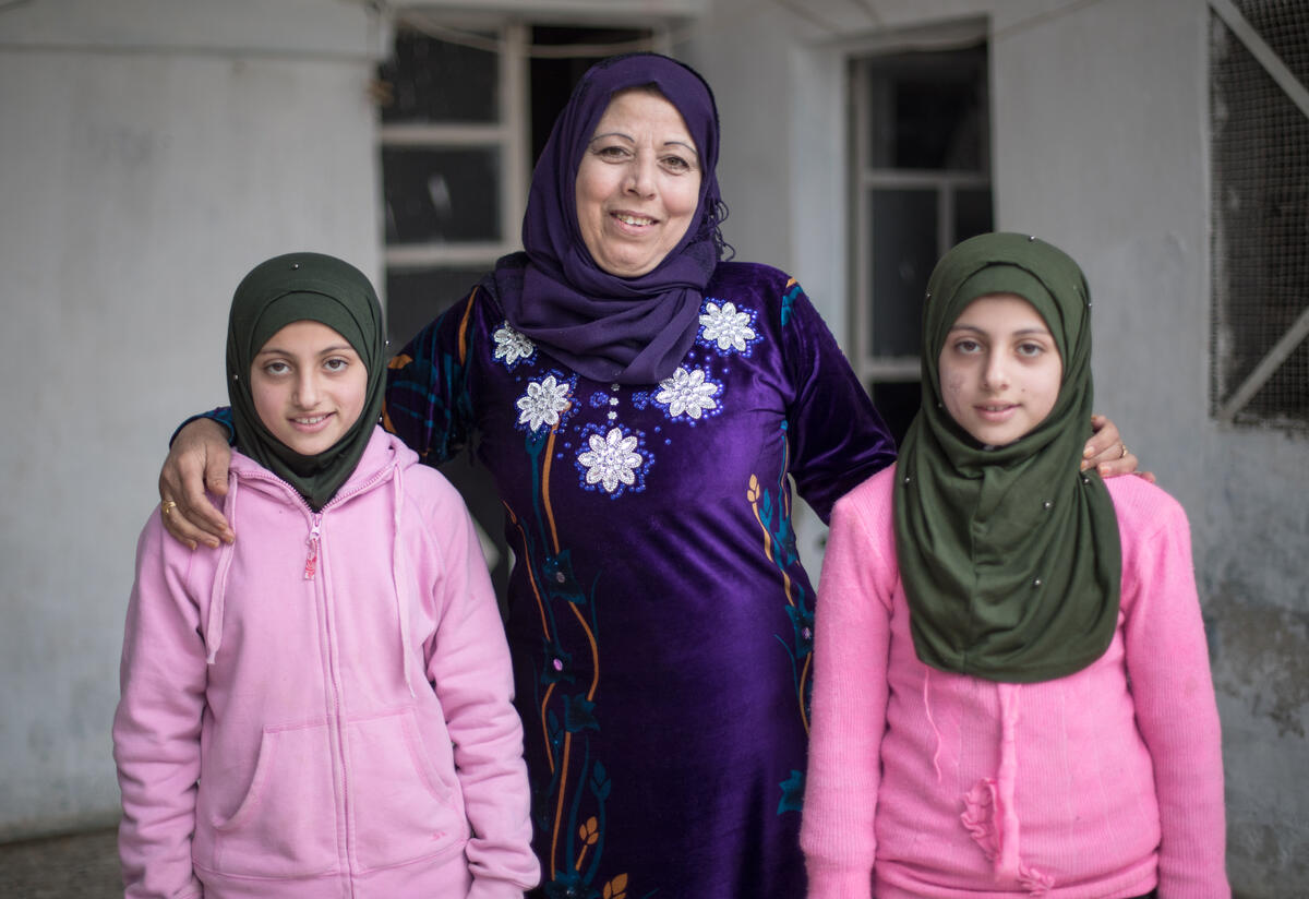 Reema stands between her twins Shurouq and Shirina with her arms around them.