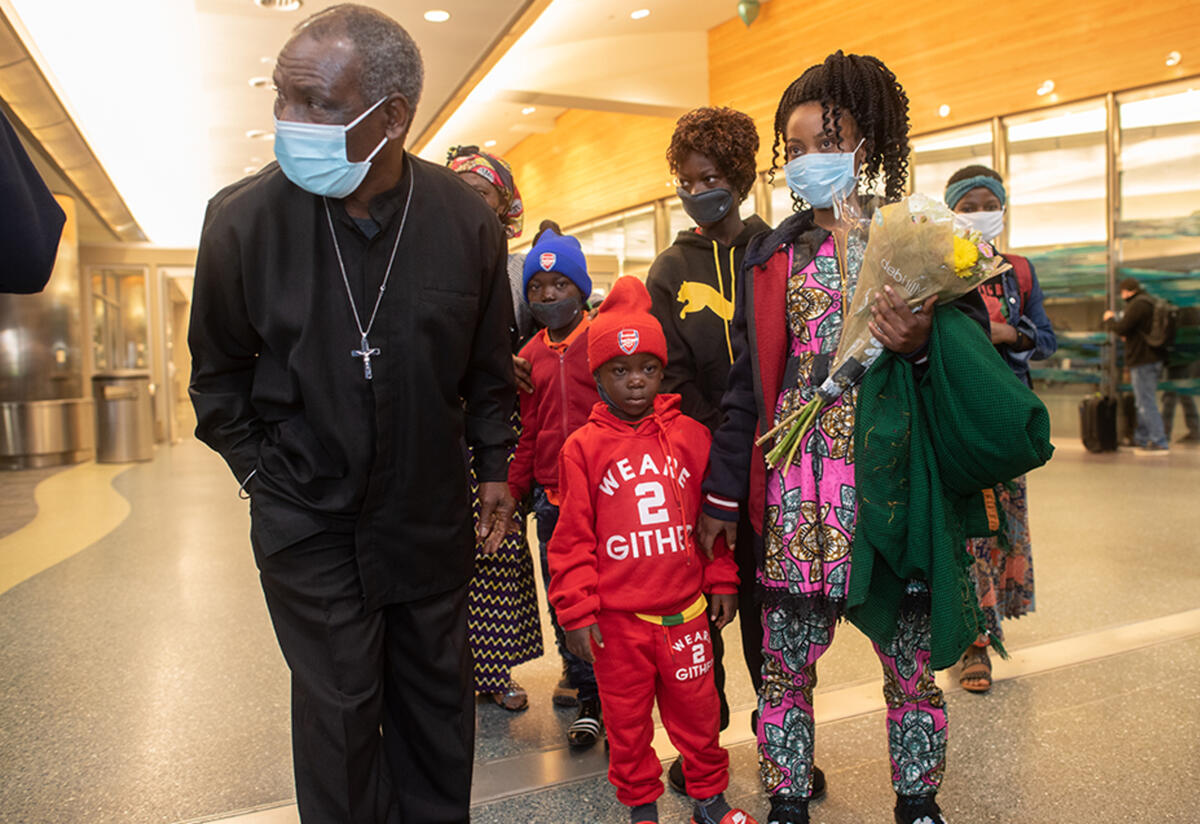 Patrice, Mauwa and family after they arrived at the airport stand in the airport. Mauwa is holdin g