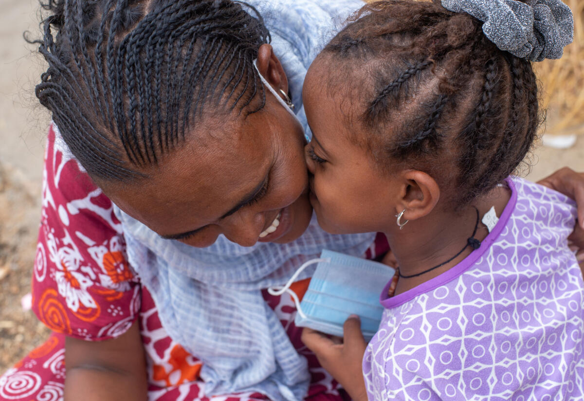 Azmera, 30, from Tigray, smiles as her young daughter kisses her cheek.