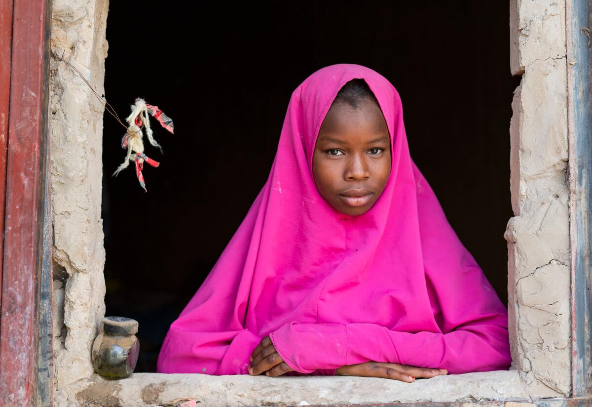 Maryama, age 15, stands framed in a window at her home in Niger.