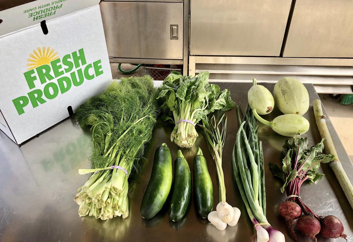 A box that says "FRESH PRODUCE" next to a variety of produce on a table.