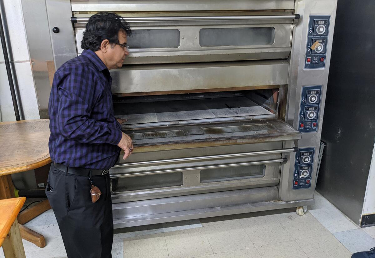 Kabul Market oven A storeowner standing next to a large oven.