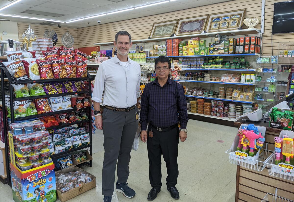 Justin Howell, Executive Director of the IRC in Atlanta, standing next to Baseer Basil, owner of Kabul Market, inside a store.