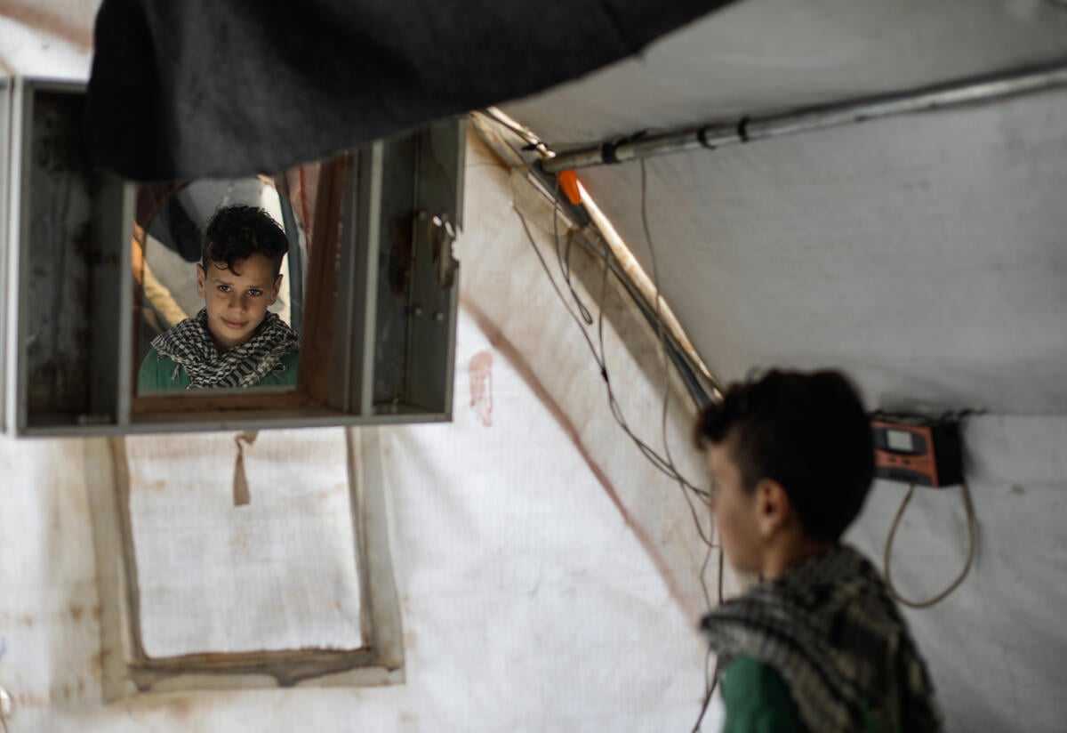 Ten-year-old Omar looks at himself in a mirror in a tent. 