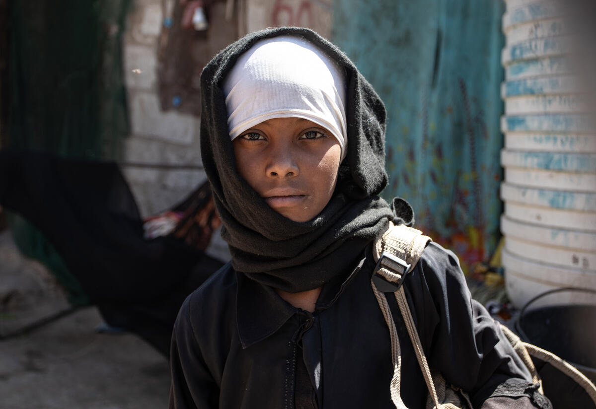Aisha, a 10-year-old girl living in a camp in southwest Yemen. A 10-year-old girl looks at the camera near her home in a camp for internally displaced people in Yemen.