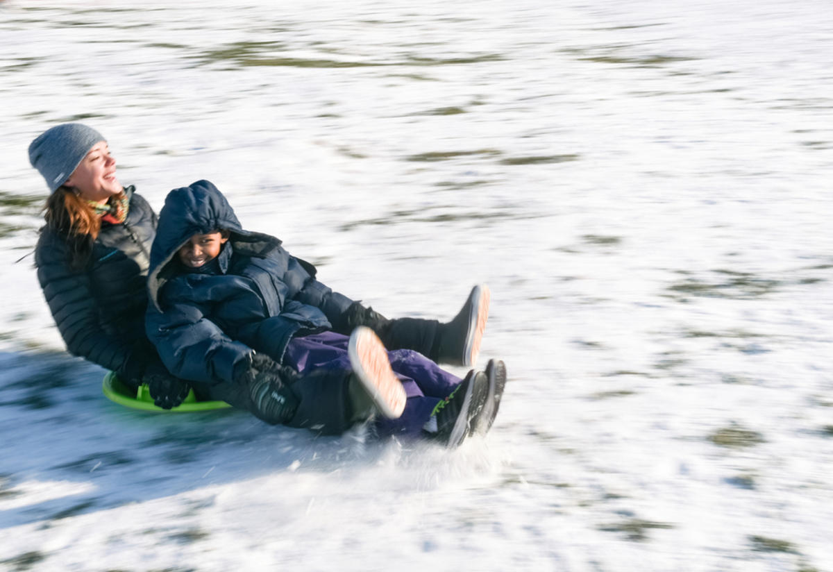 Two people sledding in Boise Family mentor Jamie Utz takes eight-year-old Muhammed sledding