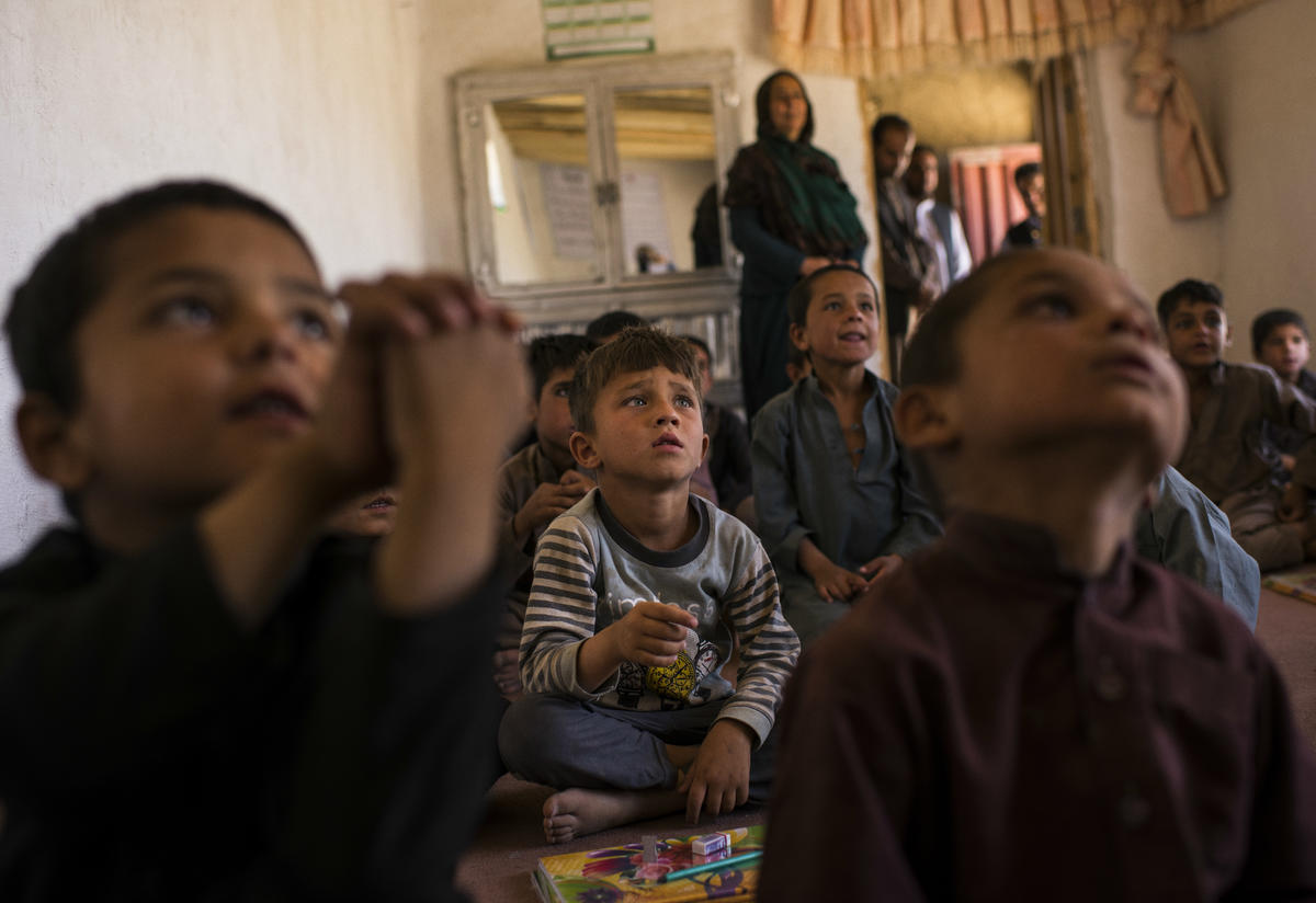 Boys listen to their teacher in an IRC-supported primary school in Afghanistan Boys sitting on the floor listen to their teacher in Afghanistan