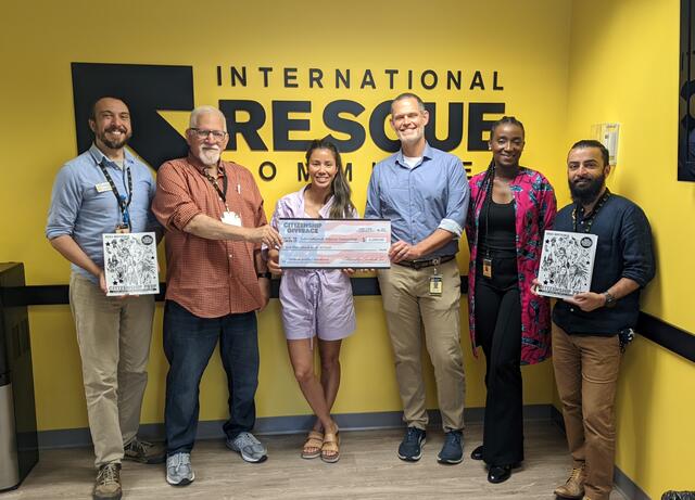 From left to right: Christopher Carpenter, Bob Gordon, Kelly Daniels, Justin Howell, Heloise Ahoure, and Ayaz Ahmed. Bob, Kelly, and Justin are all holding one large check for $1000 donated to the IRC in Atlanta. Christopher and Ayaz are each holding copies of the "Citizenship Prep" study guide.