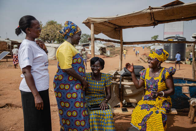 Women from refugee activist Togoleta stand around together laughing.