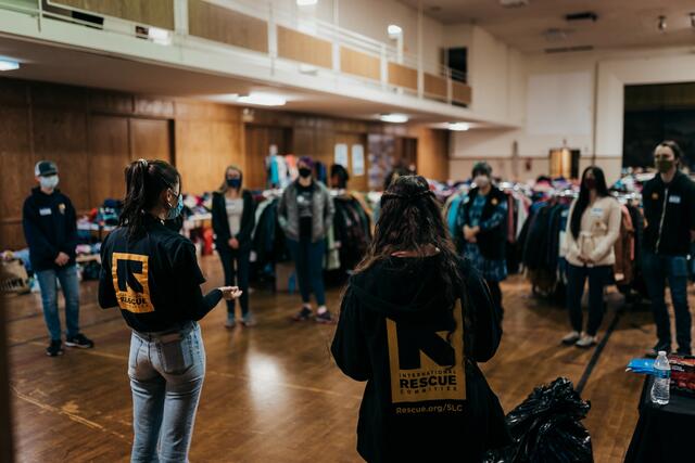 Two staff members of the IRC in Salt Lake City give instructions and orientation in front of a handful of volunteers at the Warm Welcome Winter Clothing Drive. 